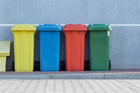 colored trash bins lined up on a curb